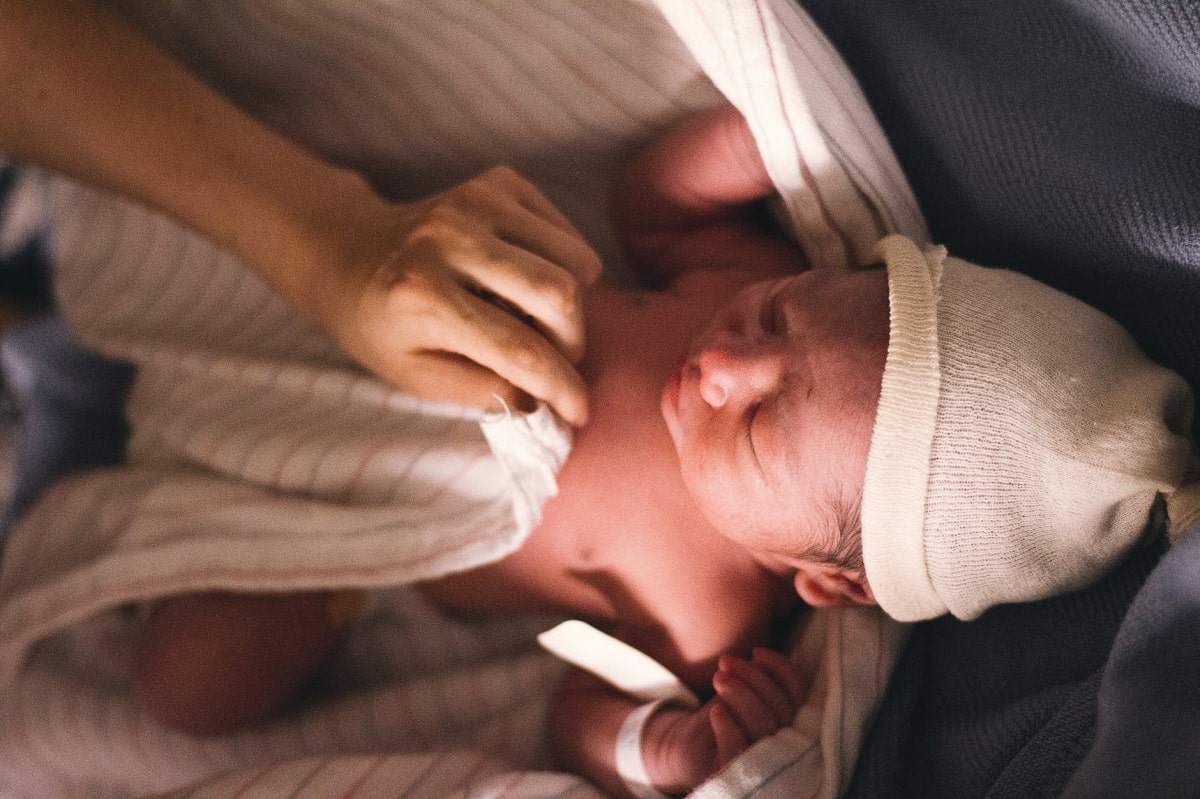 neonato accudito da una mano femminile